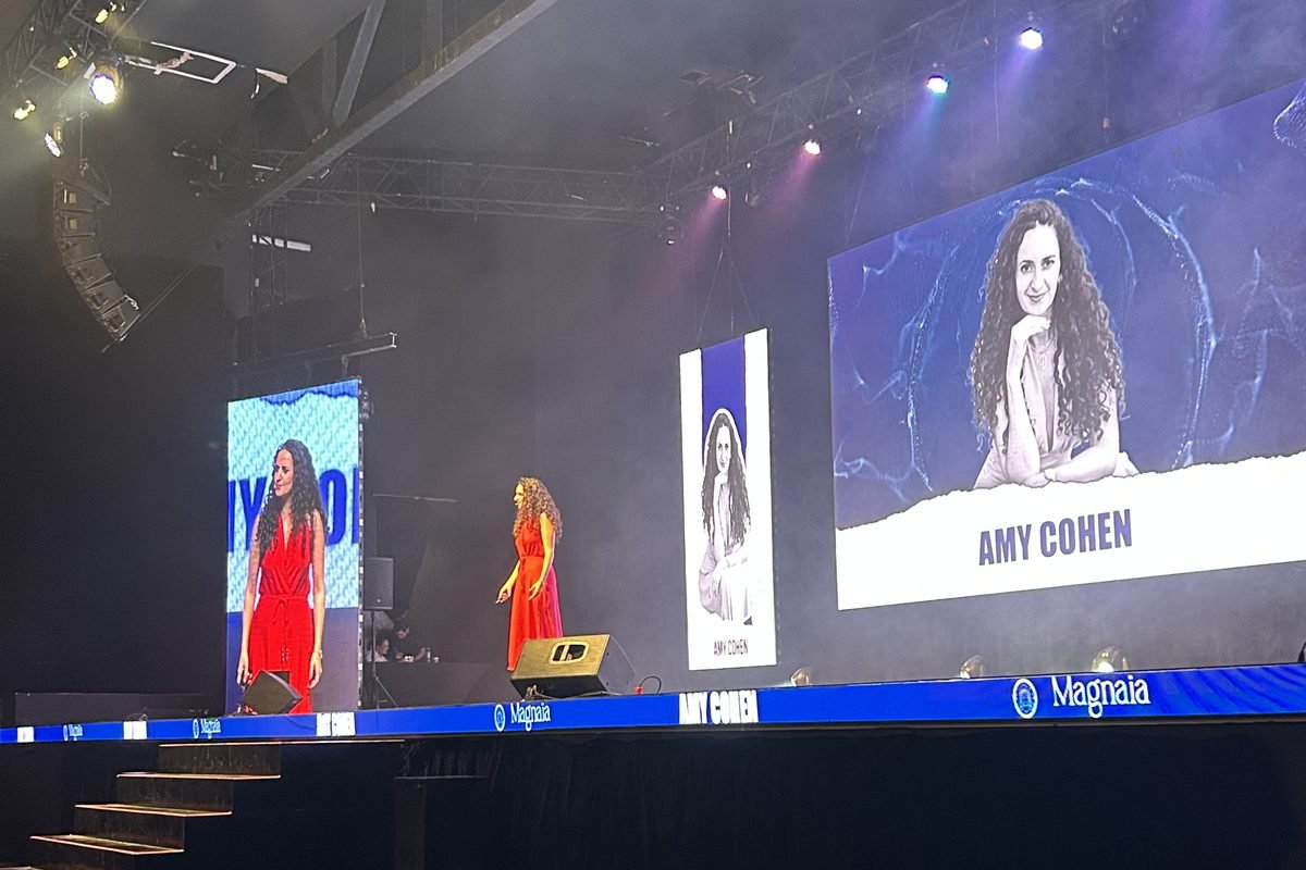 Amy Cohen en el escenario, con su nombre en la pantalla grande